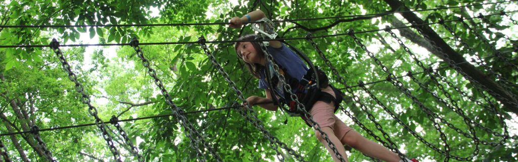 A girl going through an adventurous high chain bridge with gear on