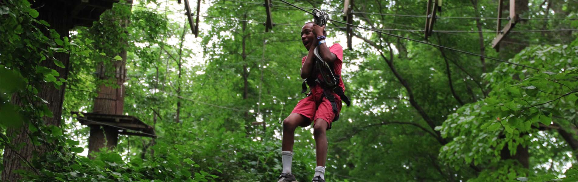 boy happily going down thru a zip line