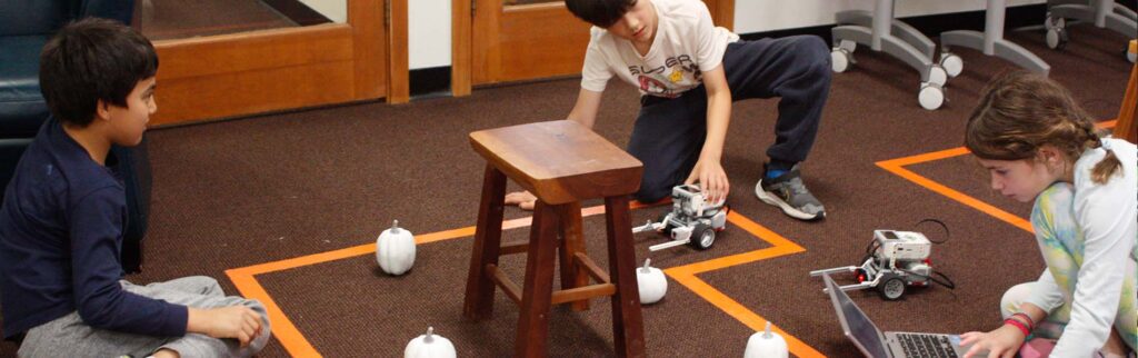 three children w/ the computer and robotic cars