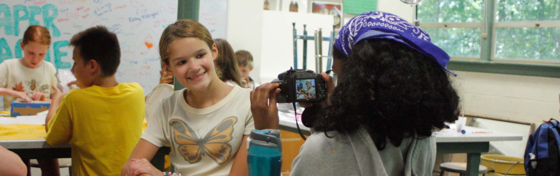young girl taking photo of another student during class
