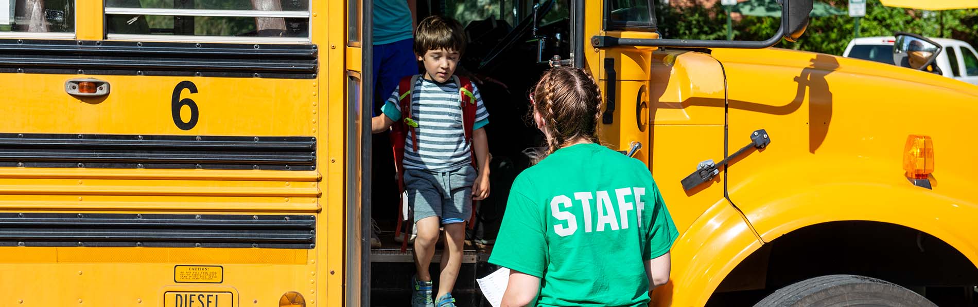 boy getting off the bus and one lady staff receiving him