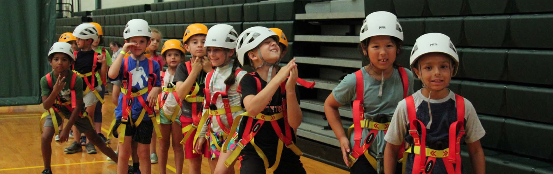 Kids with gear on and waiting in line to climb the wall